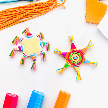 Colorful craft materials including yarn, glue sticks, and star-shaped decorations on a white background.