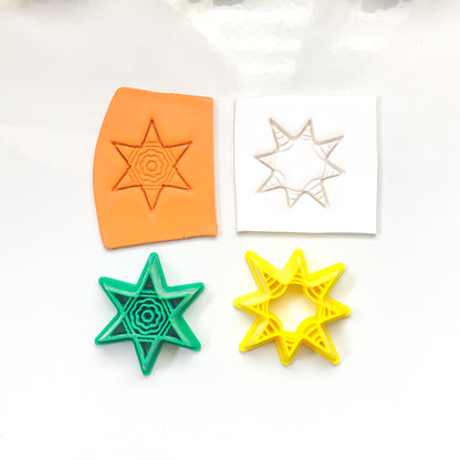 Four star-shaped cookie cutters in orange, green, yellow, and white on a white surface with Christmas decorations.