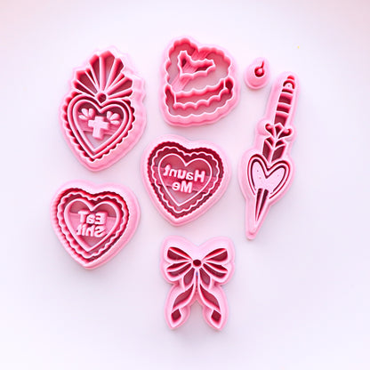 Set of pink clay cutters with heart and bow designs on a white background