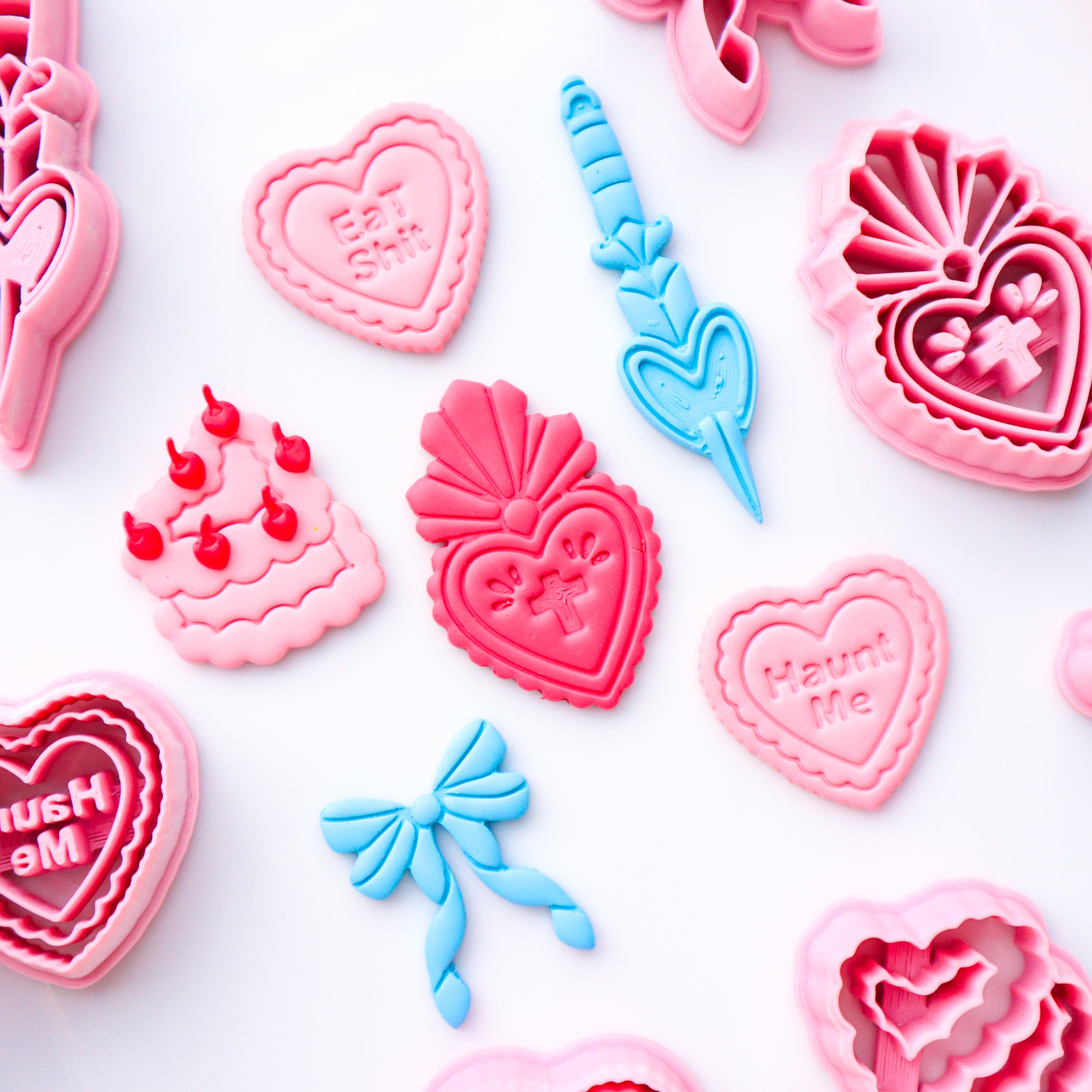 Collection of pink and blue heart-shaped polymer clay cutters on a white background